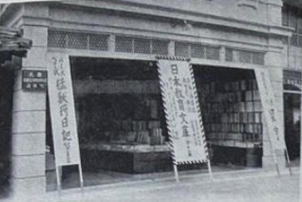 大正五年、改築後の元野木書店。洋館の店先に本が並び、「日本教育文庫」などののぼりが立っている古い白黒写真。
